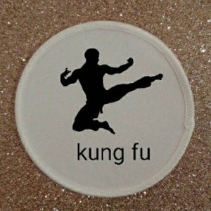 Peut inclure: Patch rond blanc avec une silhouette noire d'une personne effectuant un coup de pied de kung-fu. Le texte "kung fu" est imprimé sous la silhouette.