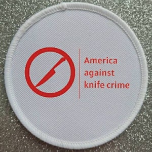 Può includere: Un cerotto rotondo bianco con testo rosso e un cerchio rosso con una linea diagonale che lo attraversa, che simboleggia un coltello. Il testo dice "America against knife crime".