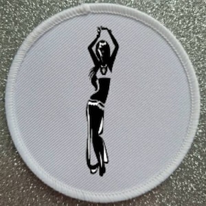 May include: White round fabric patch featuring a black silhouette of a woman dancing. The woman is wearing a long skirt and a top with a decorative belt.