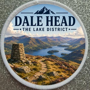 Könnte beinhalten: Ein runder bestickter Aufnäher mit einer Landschaftsillustration von Dale Head im Lake District. Das Design zeigt einen Steinhaufen im Vordergrund, einen Pfad, einen blauen See und Berge unter einem Himmel mit dem Schriftzug DALE HEAD.