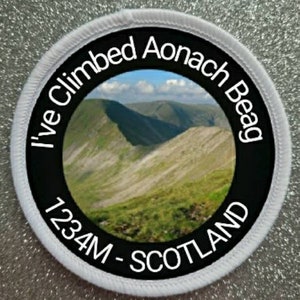 Puede incluir: Un parche redondo blanco con texto negro y una foto de una cordillera. El texto dice "I've Climbed Aonach Beag 1234M - SCOTLAND".