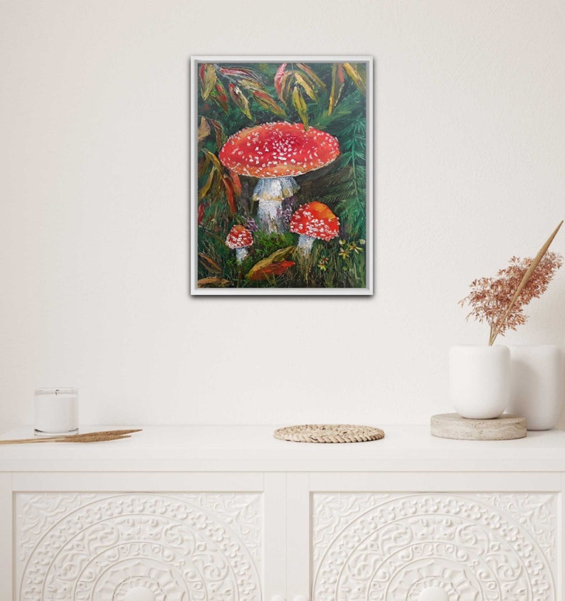 May include: A painting of three red and white mushrooms with white spots in a forest setting. The mushrooms are surrounded by green leaves and brown branches.