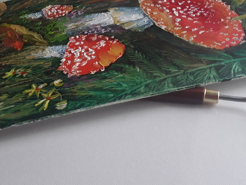 May include: A close-up of a painting of red and white mushrooms in a green forest setting. The mushrooms have white spots and are painted in a realistic style.