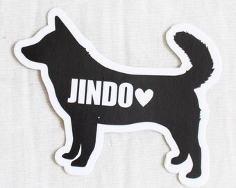May include: Black and white silhouette sticker of a Jindo dog with the word "Jindo" and a heart printed on it.
