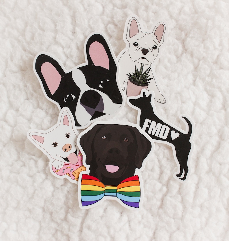 May include: Five dog stickers, each with a different design. One sticker features a black and white French bulldog with pink ears, another features a white French bulldog with a plant in a pot, another features a black Labrador Retriever wearing a rainbow bow tie, another features a white dog with a pink donut, and the last sticker features a black silhouette of a dog with the text "FMD" and a heart.
