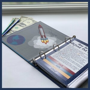 May include: A blue binder with a rocket ship graphic and the text "Beyond the". Inside, a page titled "How to Beyond the" lists financial advice. Colored bars read "Save, Give, Invest, Spend". Pencils and dollar bills are visible.
