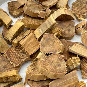 Può includere: Primo piano di un mucchio di trucioli di legno marroni. I trucioli sono di varie dimensioni e forme, e alcuni hanno una tonalità leggermente rossastra.