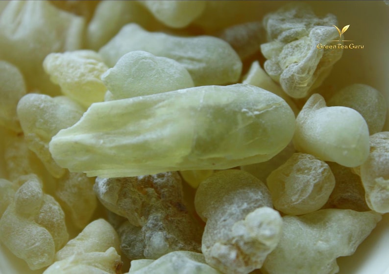 Pode incluir: Close-up de um monte de peda&ccedil;os de resina amarelo p&aacute;lido, de forma irregular. As pe&ccedil;as t&ecirc;m um aspeto ligeiramente transl&uacute;cido e uma superf&iacute;cie texturizada. A imagem destaca as varia&ccedil;&otilde;es naturais de cor e forma da resina.