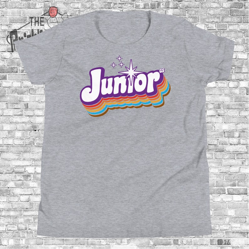 May include: Gray t-shirt with a retro-style graphic of the word "Junior" in rainbow colors with a starburst above it.