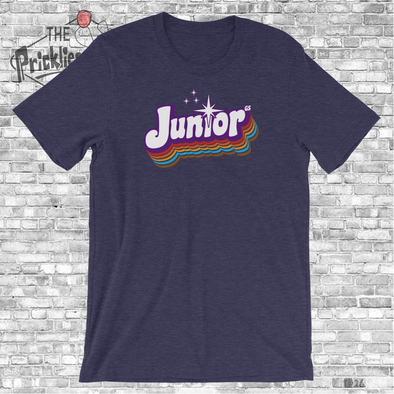 May include: A navy blue t-shirt with a retro-style graphic of the word "Junior" in rainbow colors with a star above it.