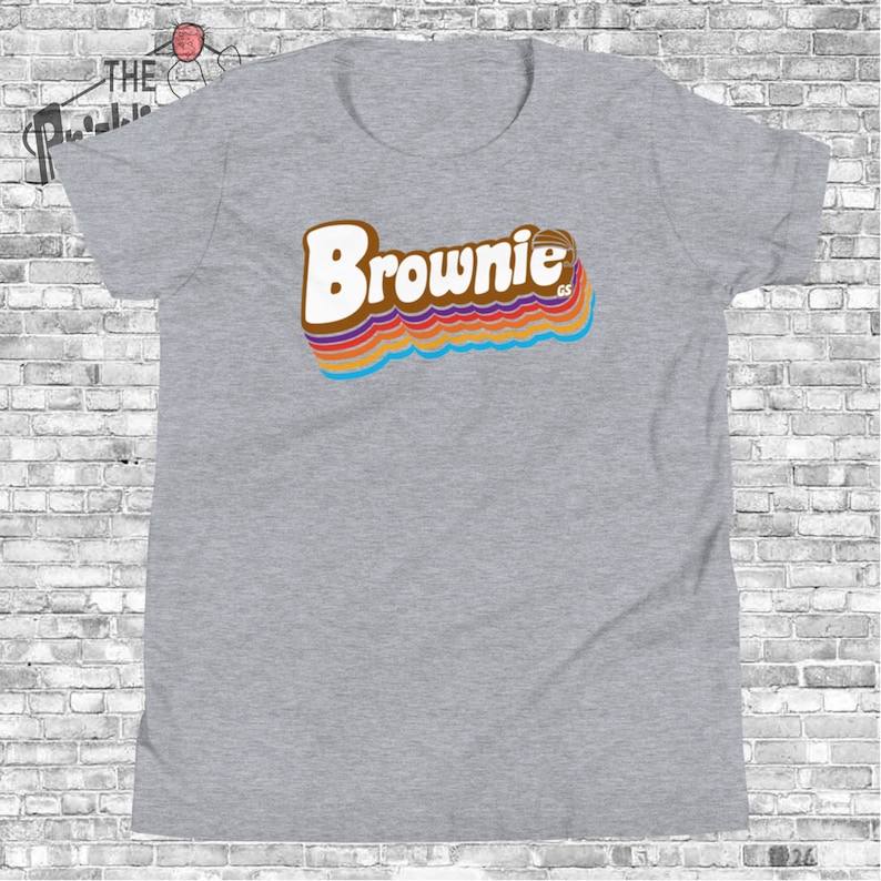 May include: Gray t-shirt with a retro-style graphic of the word "Brownie" in brown with rainbow stripes.