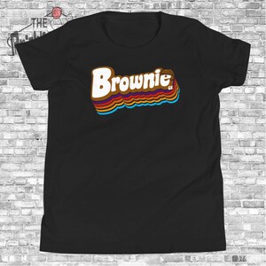May include: Black t-shirt with a retro-style graphic of the word "Brownie" in brown, orange, yellow, blue, and red colors.