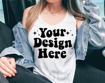 Pode incluir: Um top branco sem mangas com o texto "Your Design Here" em letras pretas de estilo retro. O top está sendo usado por uma pessoa sentada em um carro.