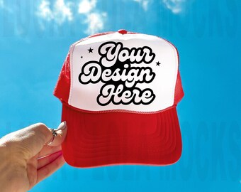 Może przedstawiać: Czapka truckerowa w kolorze czerwonym i białym z siateczką z tyłu. Z przodu czapki znajduje się czarny napis "Your Design Here" z dwoma gwiazdkami po obu stronach.