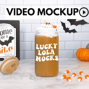 May include: A mason jar filled with a brown beverage topped with whipped cream and a candy corn. The jar has a white sticker with the text "Lucky Lola Mocks". The jar is on a white countertop with candy corn scattered around it.