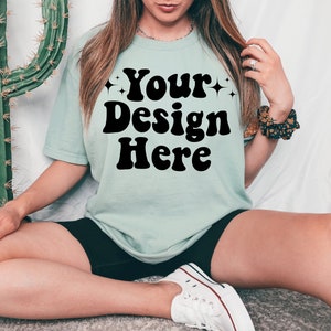 May include: A light blue t-shirt with the text "Your Design Here" in black retro-style lettering.
