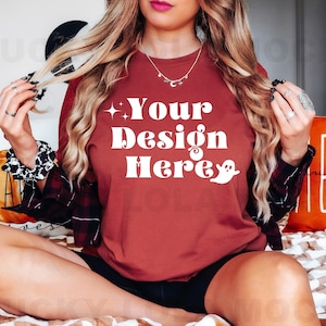 May include: A woman wearing a maroon t-shirt with the text "Your Design Here" in white. The shirt has a ghost graphic and a sparkly star.