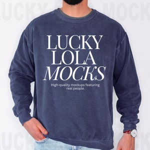 May include: A navy blue sweatshirt with the text "LUCKY LOLA MOCKS" in white. The text is stacked vertically and is centred on the sweatshirt. Below the text is the phrase "High-quality mockups featuring real people."