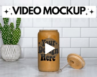 May include: A brown tumbler with a lid and straw. The tumbler has a white sticker with the text "Your Design Here" and a play button icon.