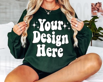 May include: A dark green sweatshirt with the text "Your Design Here" in white retro-style lettering. The sweatshirt has long sleeves and a crew neck.