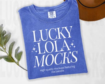 May include: A blue t-shirt with the text "LUCKY LOLA MOCKS" in white. The text is surrounded by small white stars. The shirt has a distressed look and is made of a soft, comfortable fabric. The text "High-quality mockups featuring real people." is printed below the main text.
