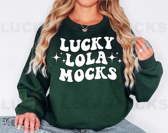 May include: A dark green sweatshirt with white text that reads "Lucky Lola Mocks" with white stars on either side of the word "Lola".