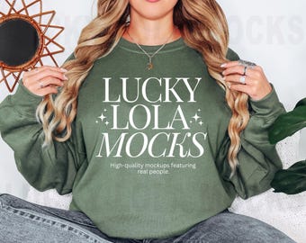 May include: A green sweatshirt with the text "LUCKY LOLA MOCKS" in white lettering. The text is centred on the sweatshirt and is surrounded by small white stars. Below the text is the phrase "High-quality mockups featuring real people."