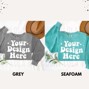 May include: Two sweatshirts, one grey and one teal, with the text "Your Design Here" in a retro font. Both sweatshirts have a relaxed fit and long sleeves.