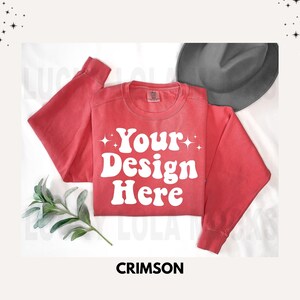 May include: Crimson red sweatshirt with a white graphic that says "Your Design Here" in a retro font. The sweatshirt is laying flat on a white surface.