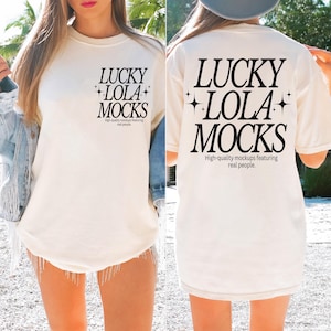May include: A cream-coloured t-shirt featuring the text "LUCKY LOLA MOCKS" in black, with star details. The shirt also has the text "High-quality mockups featuring real people." The t-shirt is being worn.