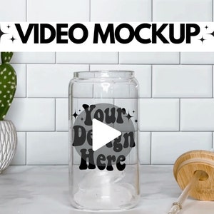 May include: A clear glass water bottle with a black and white design that says "Your Design Here" and a play button icon. The bottle has a bamboo lid and a straw.