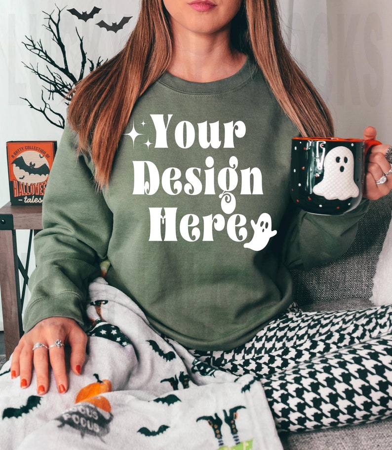 May include: A green sweatshirt with the text "Your Design Here" in white retro font. The sweatshirt is worn by a person holding a black and white ghost mug.