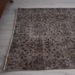 May include: A vintage-style rug with a brown and cream floral pattern. The rug has a distressed look and is made of a soft, woven material.