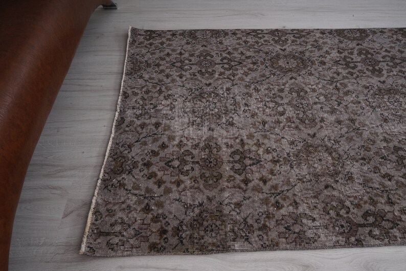 May include: A vintage-style rug with a brown and cream floral pattern. The rug has a distressed look and is made of a soft, woven material.