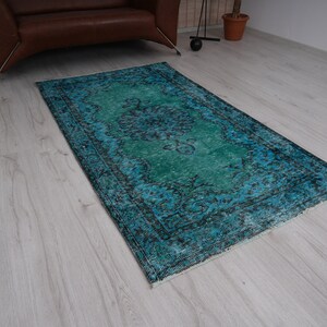 May include: A vintage teal and blue rug with a faded floral pattern. The rug has a distressed look and is perfect for adding a touch of bohemian style to any room.