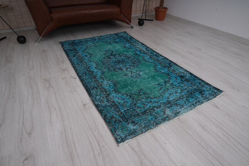 May include: A vintage teal and blue rug with a faded floral pattern. The rug has a distressed look and is perfect for adding a touch of bohemian style to any room.