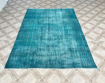 May include: A teal blue vintage rug with a faded, distressed look. The rug has a subtle pattern and a worn, antique appearance.