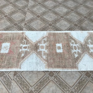May include: A white and brown patterned runner rug with a geometric design. The rug has a distressed look and is made of natural fibers.