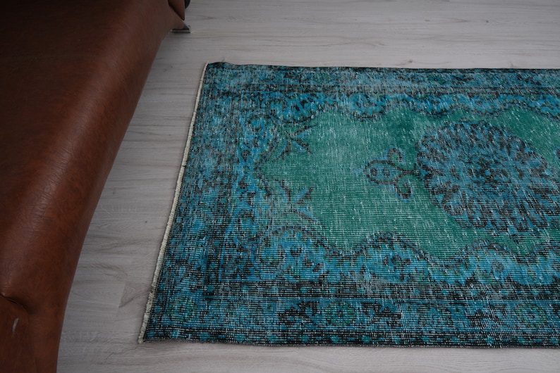 May include: A vintage teal and blue rug with a floral pattern. The rug has a distressed look and is made of a soft, woven material.