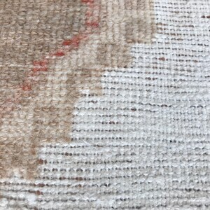 May include: Close-up of a beige and white woven rug with a textured surface.
