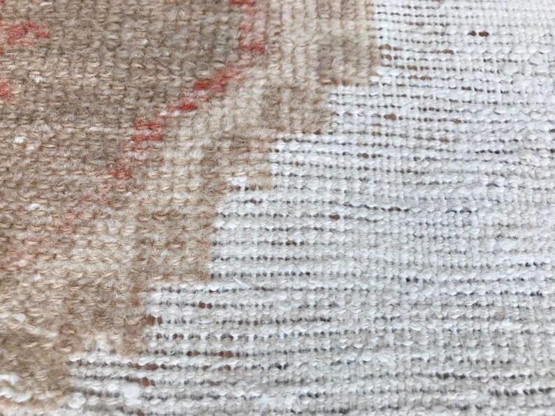 May include: Close-up of a beige and white woven rug with a textured surface.