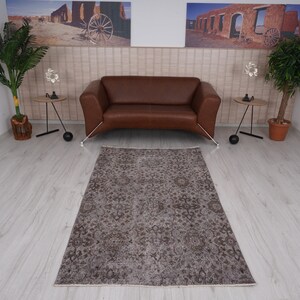 May include: A brown patterned rug with a distressed look, placed in front of a brown leather sofa in a living room setting.