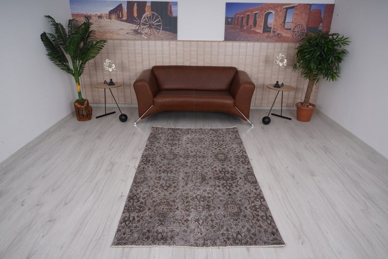 May include: A brown patterned rug with a distressed look, placed in front of a brown leather sofa in a living room setting.