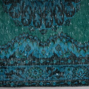 May include: Close-up of a blue and green patterned rug with a textured woven design.