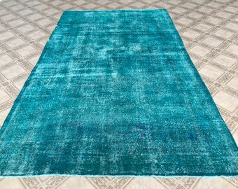 May include: A teal blue rug with a distressed, vintage look. The rug has a subtle pattern and a soft, faded appearance.