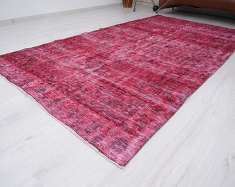 Könnte beinhalten: Ein Vintage-Teppich mit einem verblassten rosa und schwarzen Muster. Der Teppich hat einen abgenutzten Look und ist aus einem weichen, gewebten Material gefertigt.