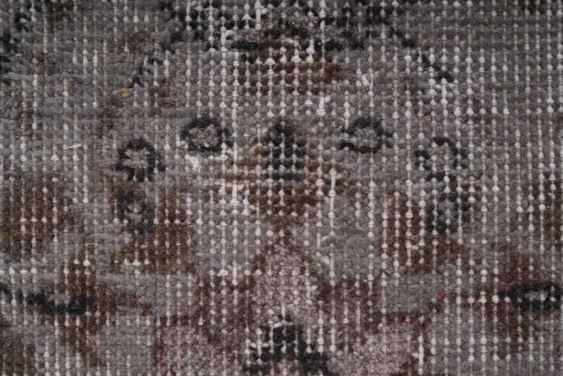 May include: Close-up of a textured fabric with a repeating pattern of small white, brown, and black dots. The fabric has a subtle sheen and a slightly rough texture.