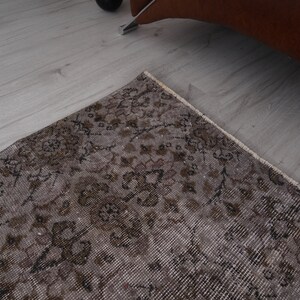May include: A vintage rug with a floral pattern in shades of brown and beige. The rug has a distressed look and is made of a soft, woven material.