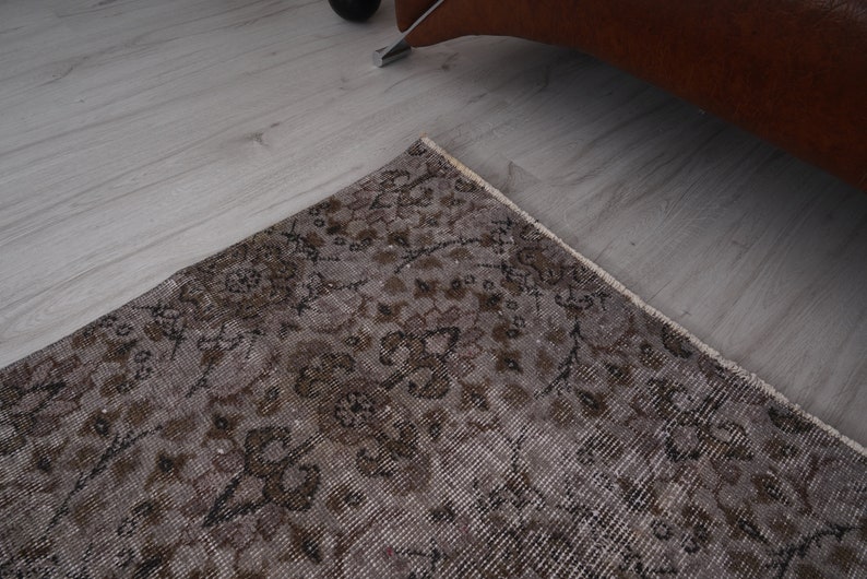 May include: A vintage rug with a floral pattern in shades of brown and beige. The rug has a distressed look and is made of a soft, woven material.