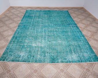 May include: A teal blue vintage rug with a faded, distressed look. The rug has a subtle pattern and a fringed edge.